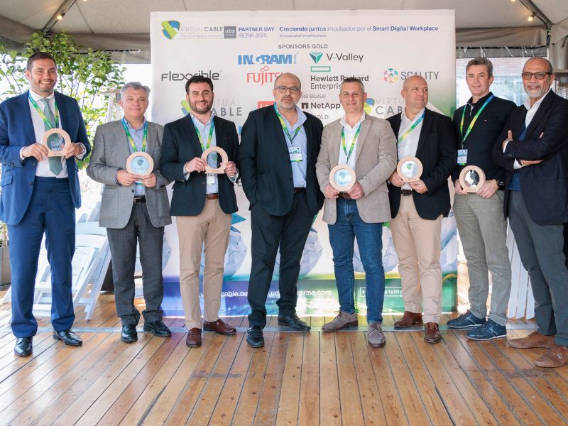 Ganadores de los premios Virtual Cable Partner Day Iberia 2025 posando con sus trofeos, con el fondo de patrocinadores del evento.